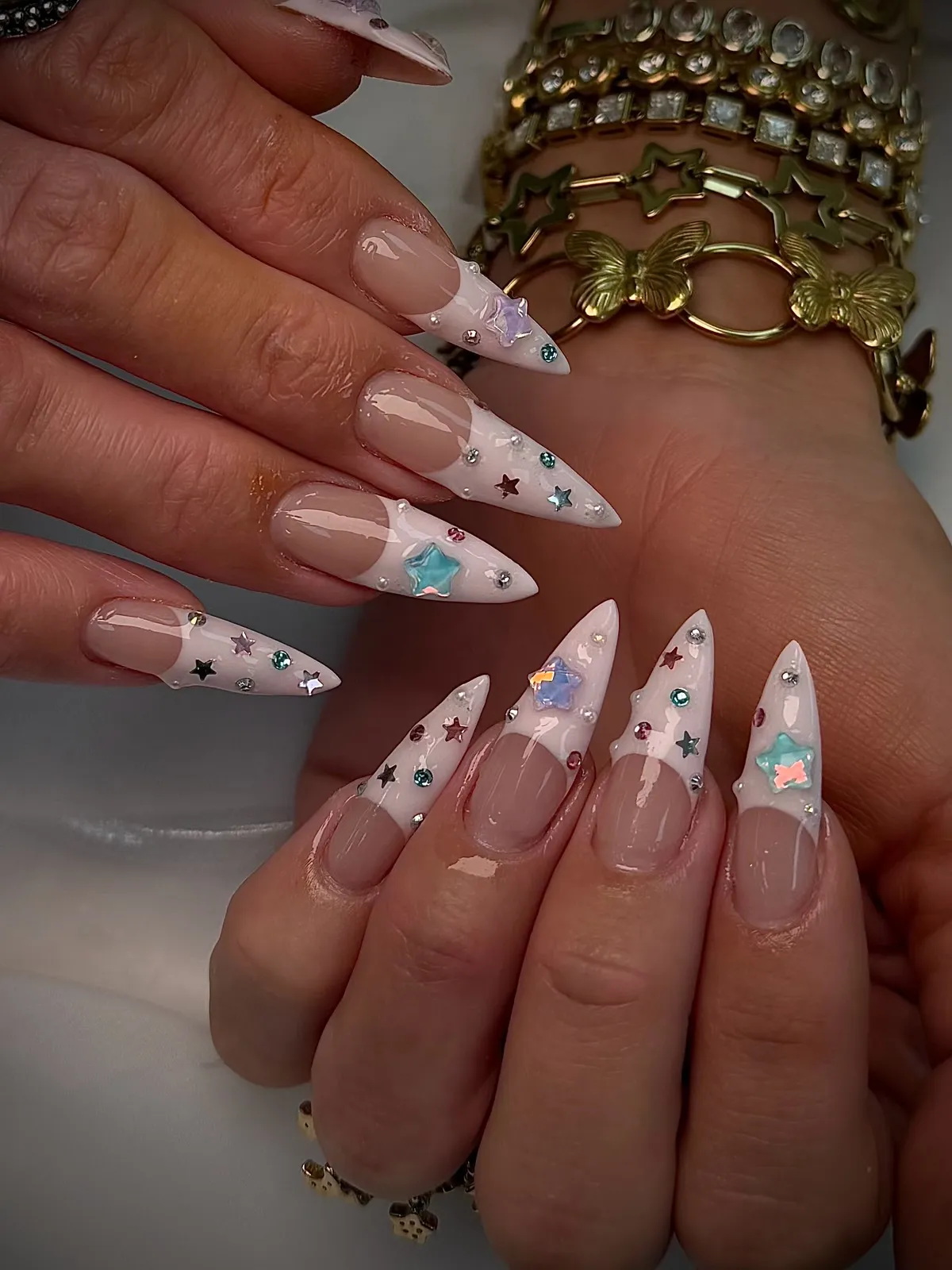 Long stilettos with milky white french tips, scattered with tiny rhinestones, small stars and iridescent star charms.