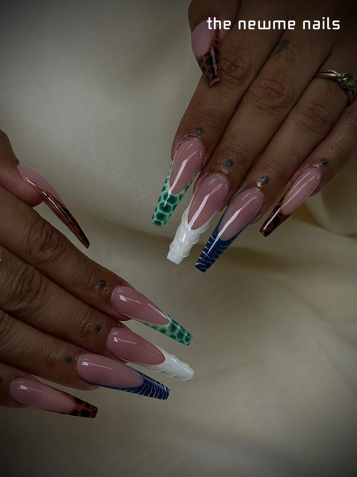 Long coffin nails on a pink base with french tips in green crocodile, white sculpted swirls, navy stripes and tortoiseshell.